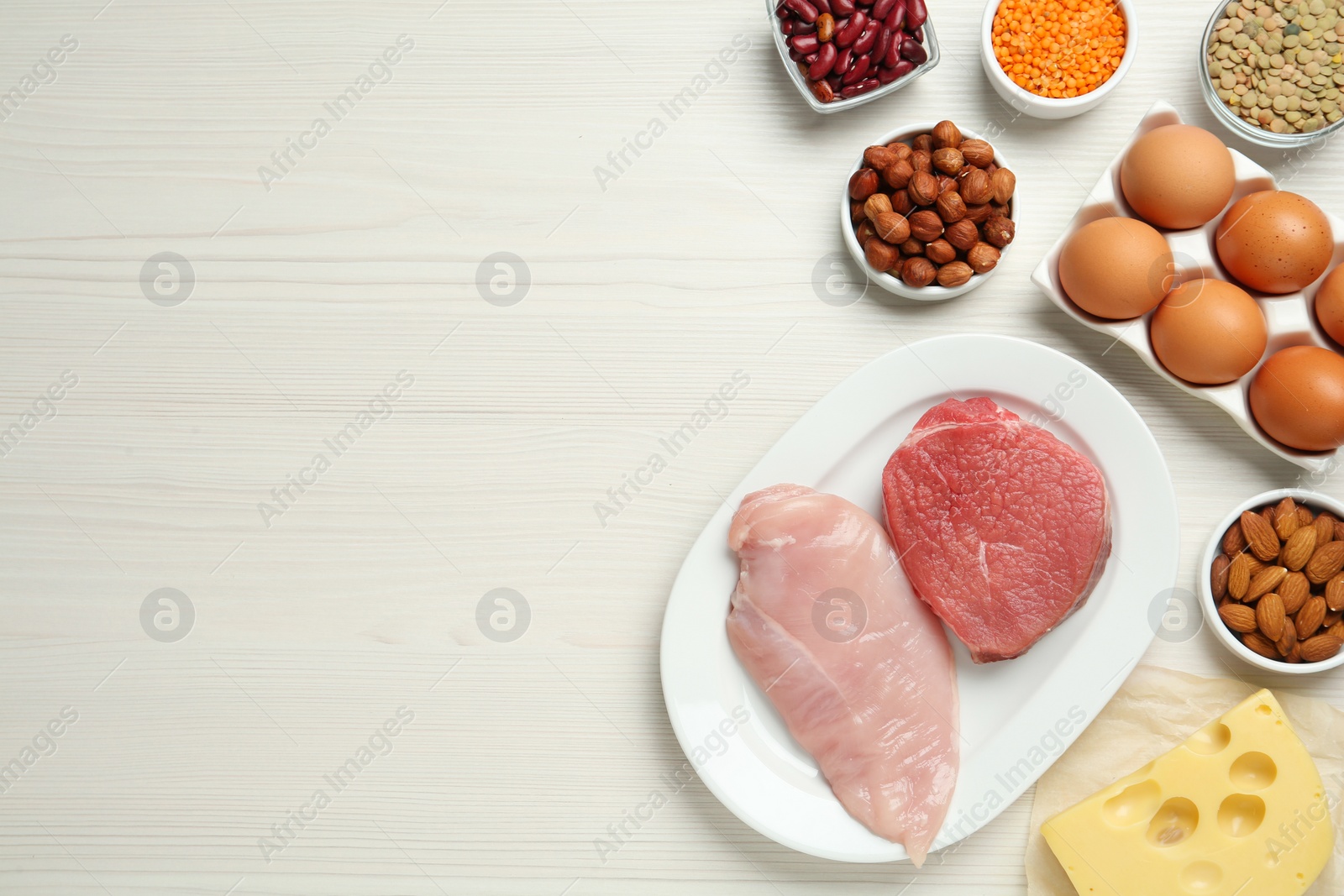 Photo of Different fresh products on white wooden table, flat lay and space for text. Sources of essential amino acids