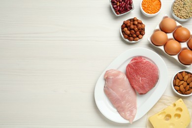 Different fresh products on white wooden table, flat lay and space for text. Sources of essential amino acids