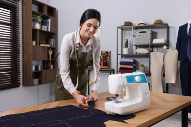 Photo of Dressmaker cutting fabric by following chalked sewing pattern in workshop