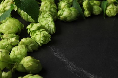 Fresh green hops and leaves on black table, closeup