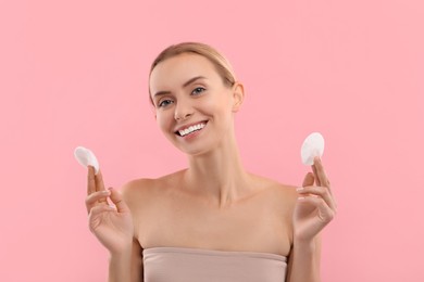 Removing makeup. Smiling woman with cotton pads on pink background