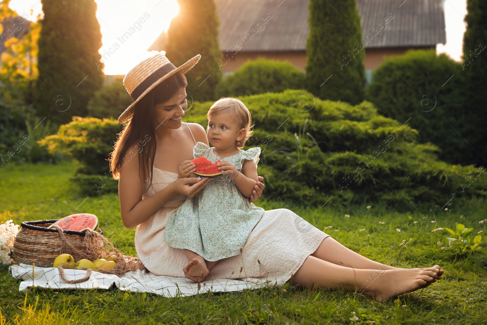 Photo of Mother with her baby daughter having picnic in garden on sunny day