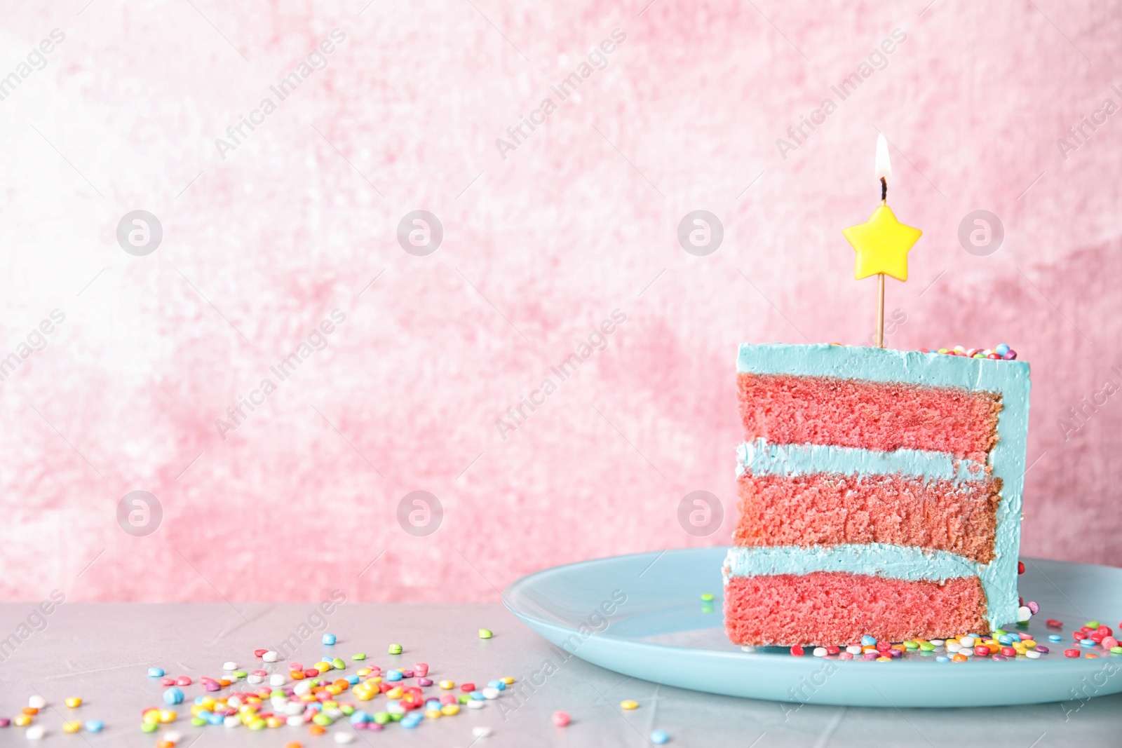 Photo of Slice of fresh delicious birthday cake with candle on table against color background. Space for text