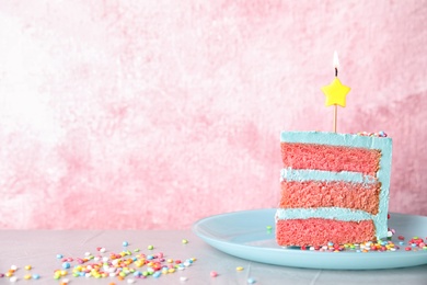 Photo of Slice of fresh delicious birthday cake with candle on table against color background. Space for text