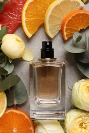 Photo of Flat lay composition with bottle of perfume and fresh citrus fruits on light grey table