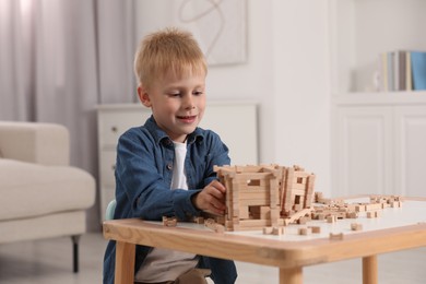 Cute little boy playing with wooden blocks at table indoors. Child's toy