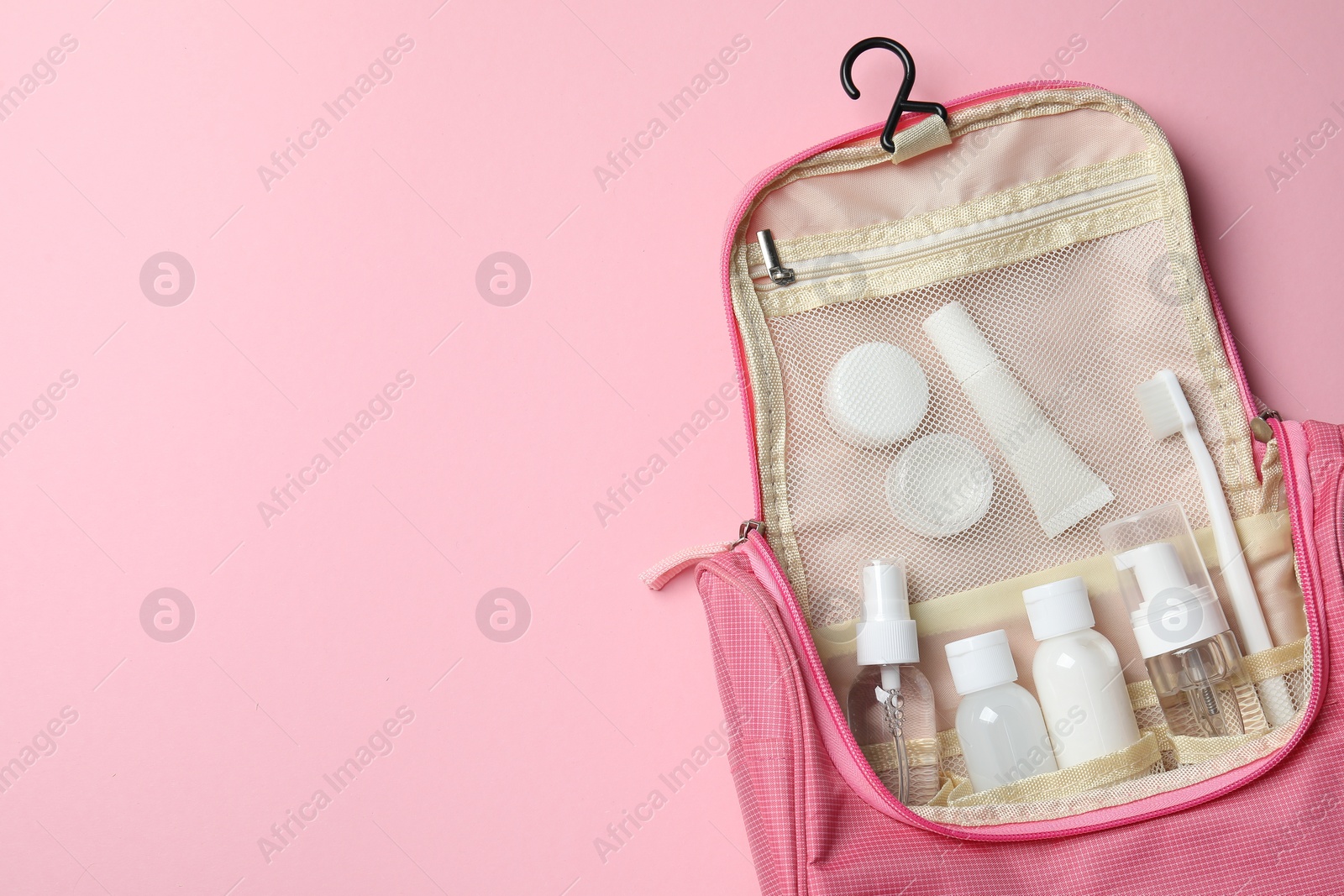 Photo of Compact toiletry bag with cosmetic travel kit on pink background, top view and space for text. Bath accessories
