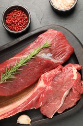 Pieces of raw beef meat and spices on grey table, flat lay