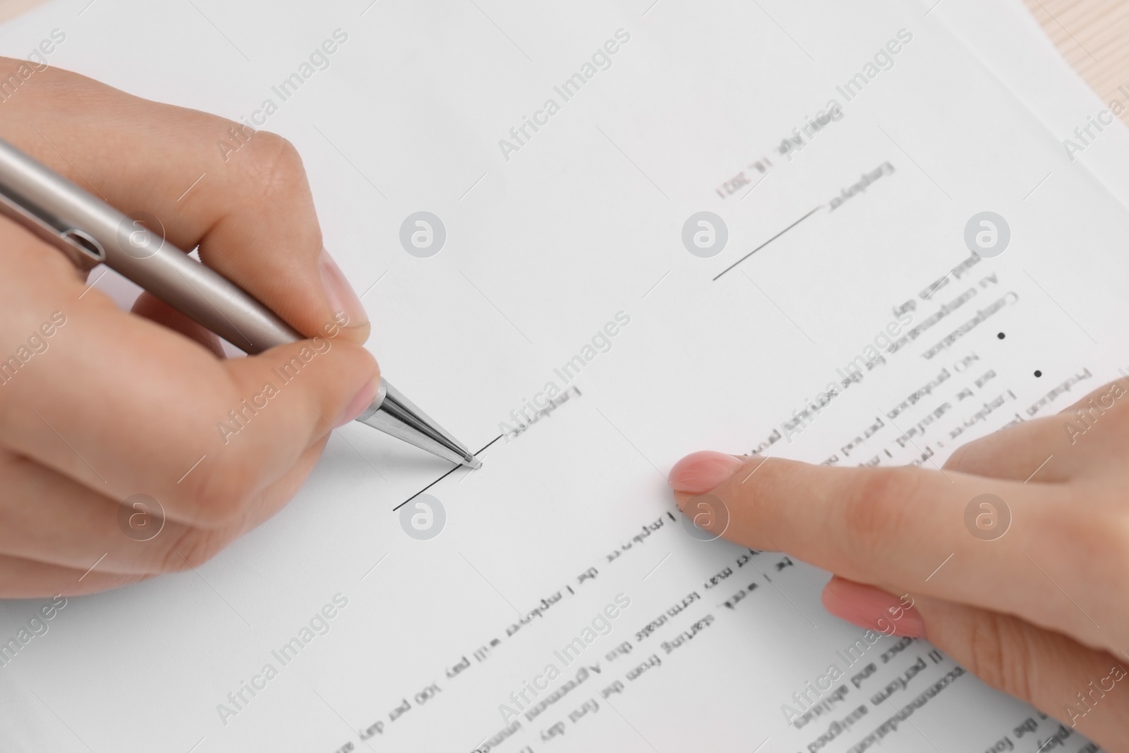 Photo of Woman pointing at document and man putting signature, closeup view