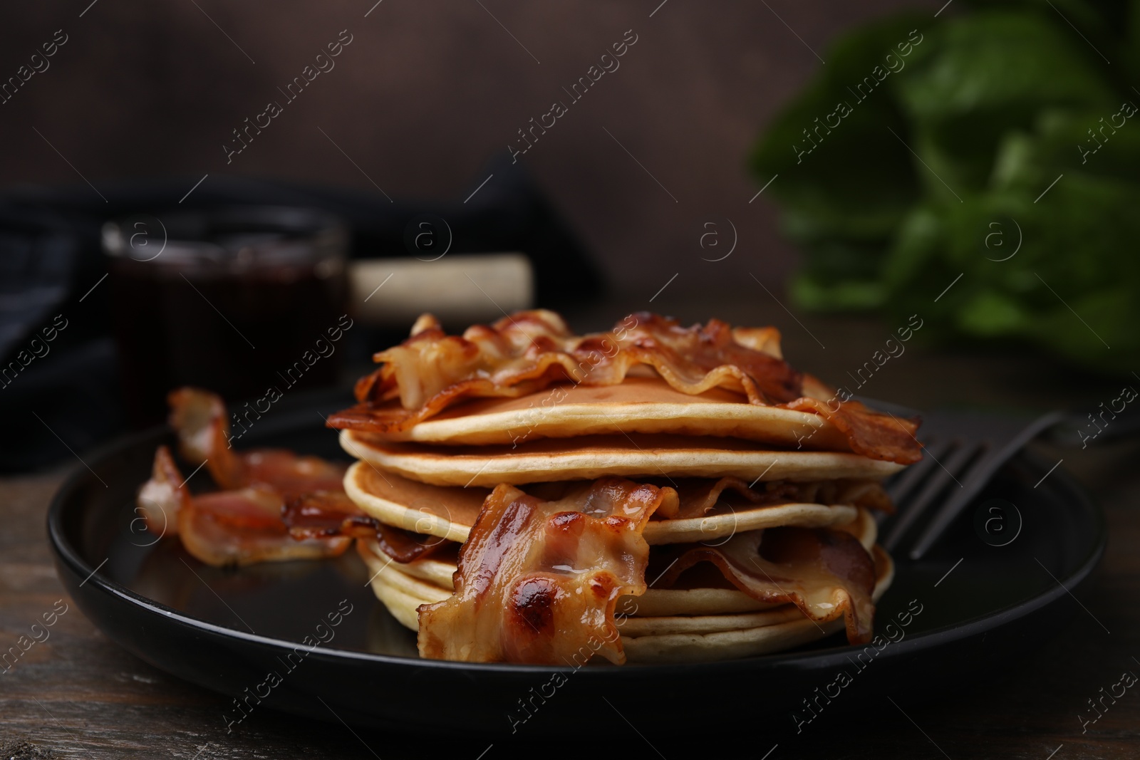 Photo of Delicious pancakes with fried bacon served on wooden table, closeup