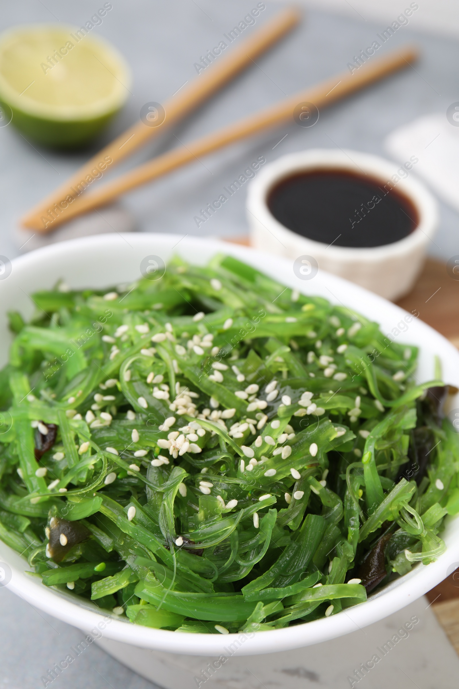 Photo of Tasty seaweed salad in bowl served on gray table, closeup