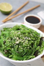 Photo of Tasty seaweed salad in bowl served on gray table, closeup