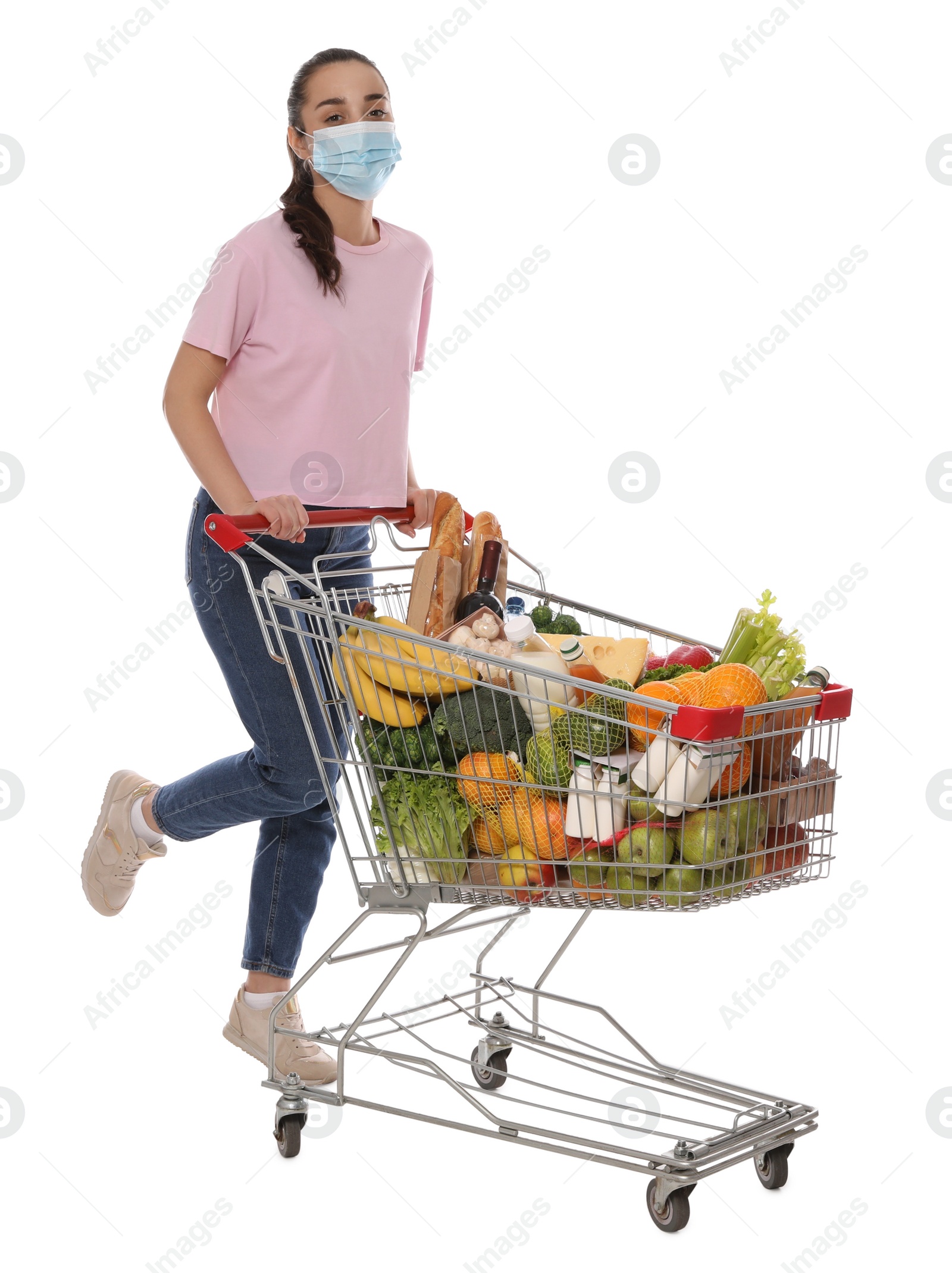 Photo of Woman with protective mask and shopping cart full of groceries on white background