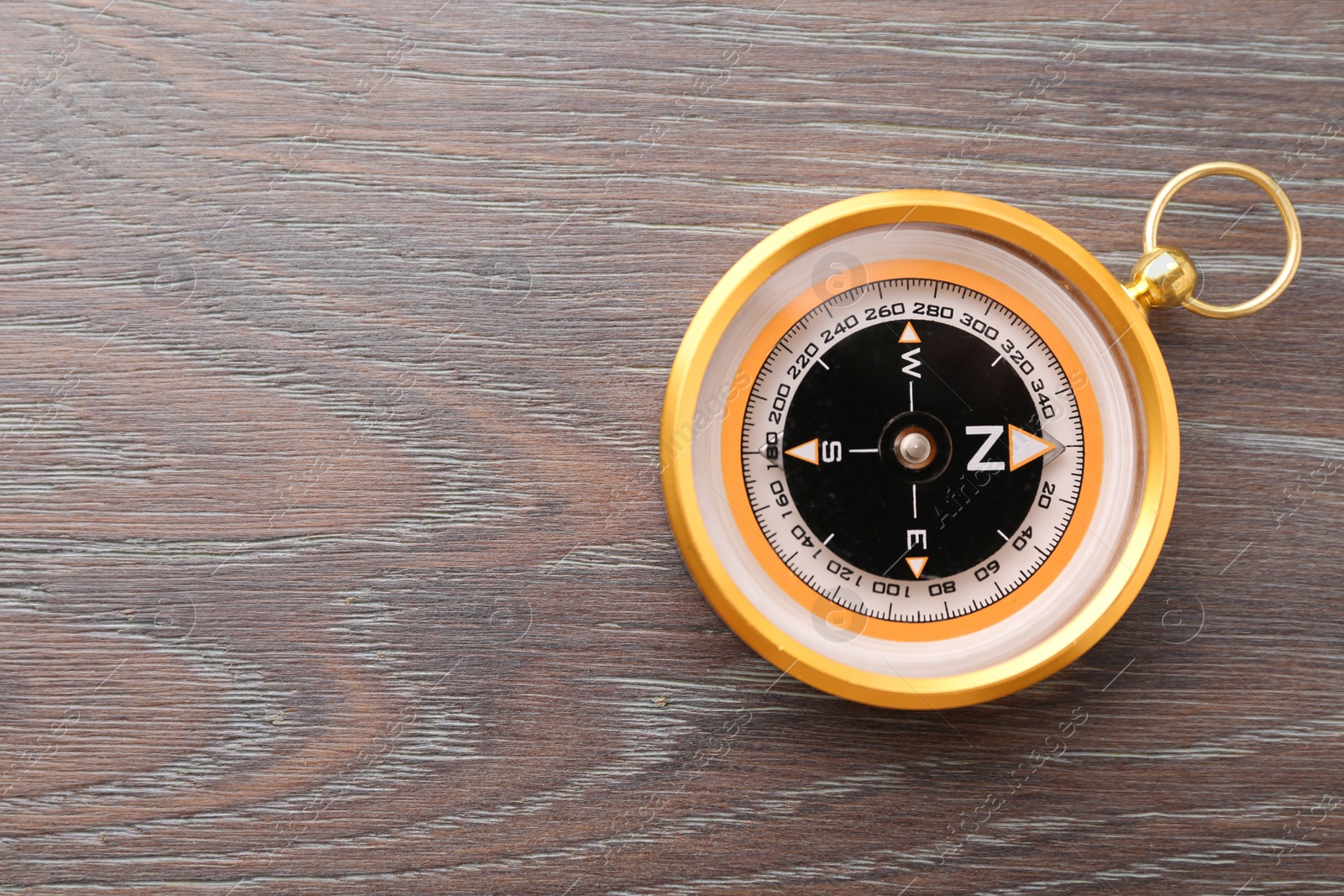 Photo of One compass on wooden table, top view. Space for text