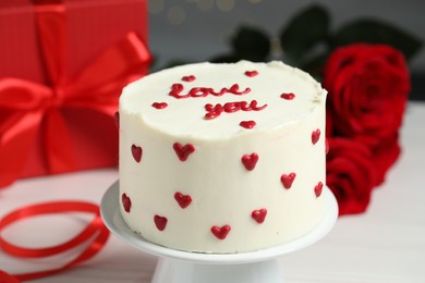 Photo of Bento cake with text Love You, gift box and roses on white table, closeup. St. Valentine's day surprise