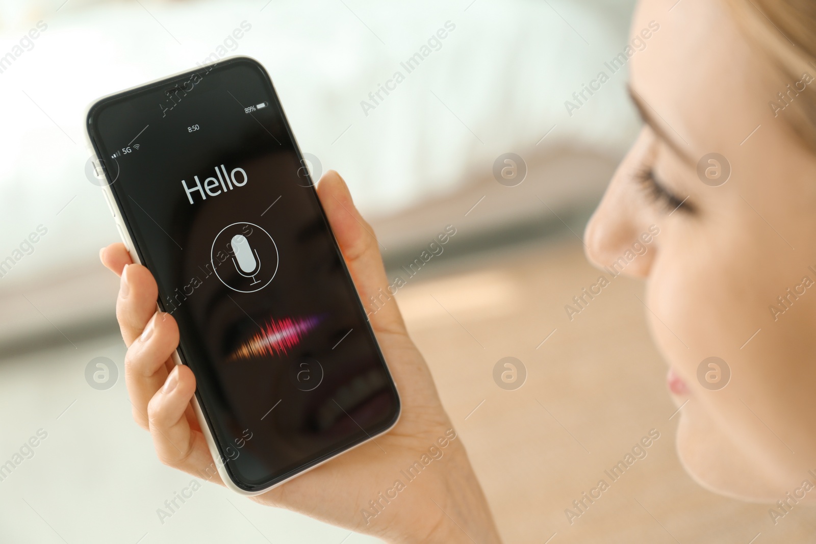 Photo of Young woman using voice search on smartphone indoors, closeup