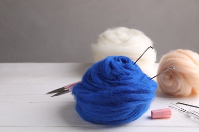 Photo of Felting wool and tools on white wooden table. Space for text