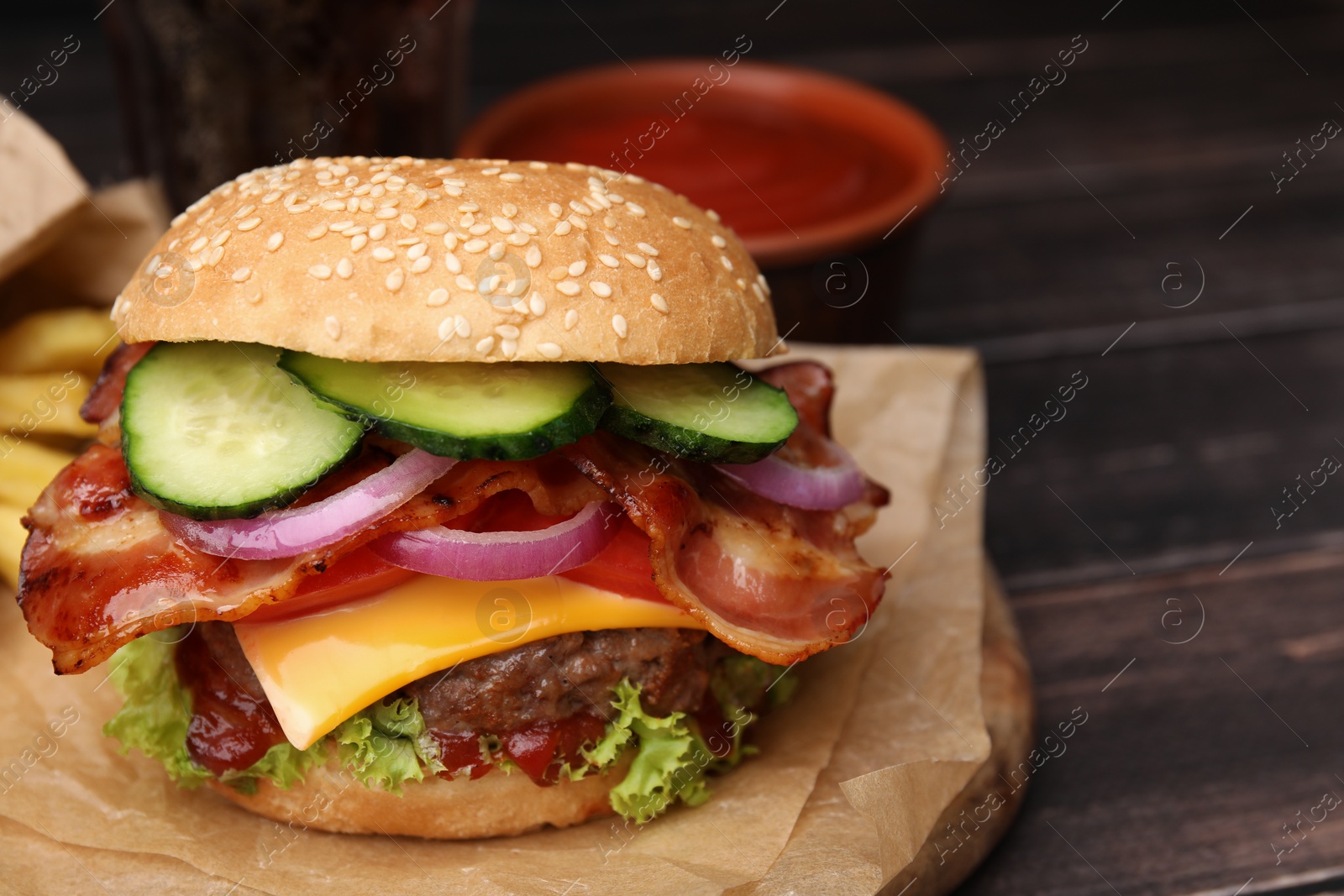 Photo of Tasty burger with bacon, vegetables and patty on wooden table, closeup. Space for text