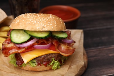 Tasty burger with bacon, vegetables and patty on wooden table, closeup. Space for text