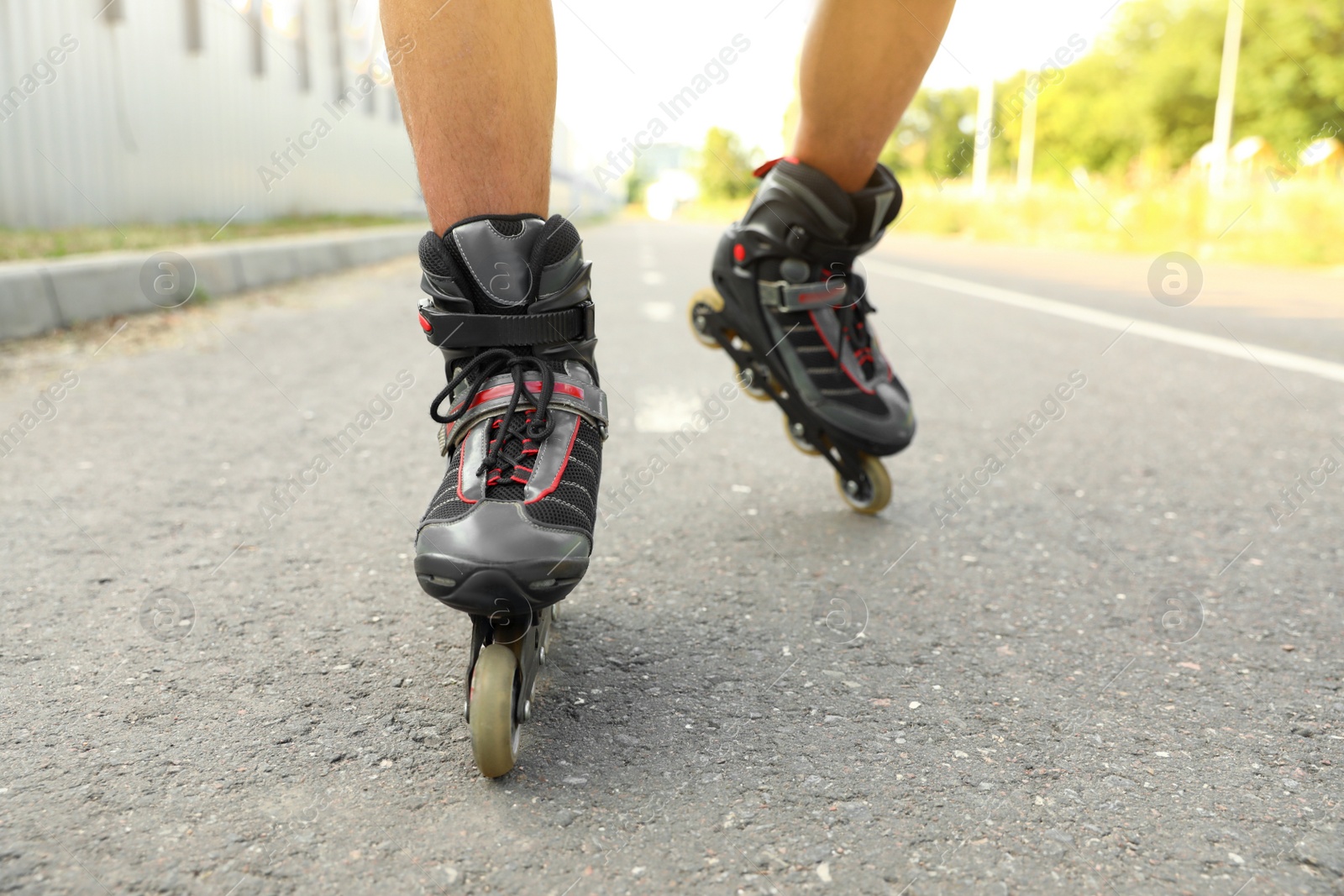 Photo of Young man roller skating outdoors, closeup. Recreational activity