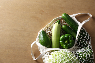 Photo of Different fresh vegetables in eco mesh bag on wooden table, top view