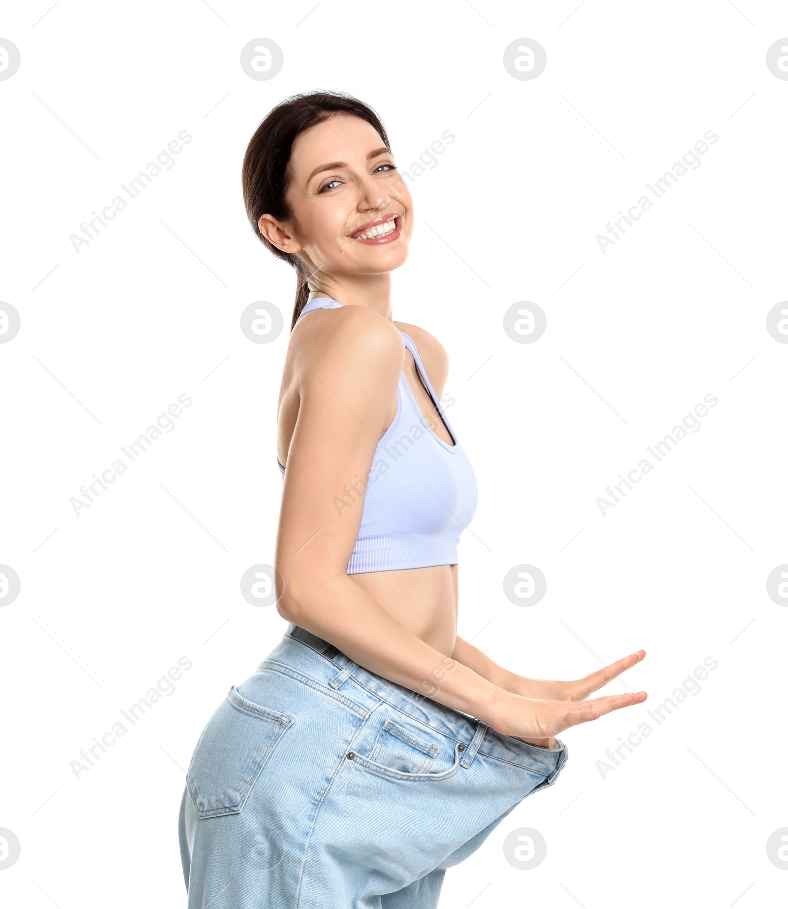 Photo of Happy young woman in big jeans showing her slim body on white background