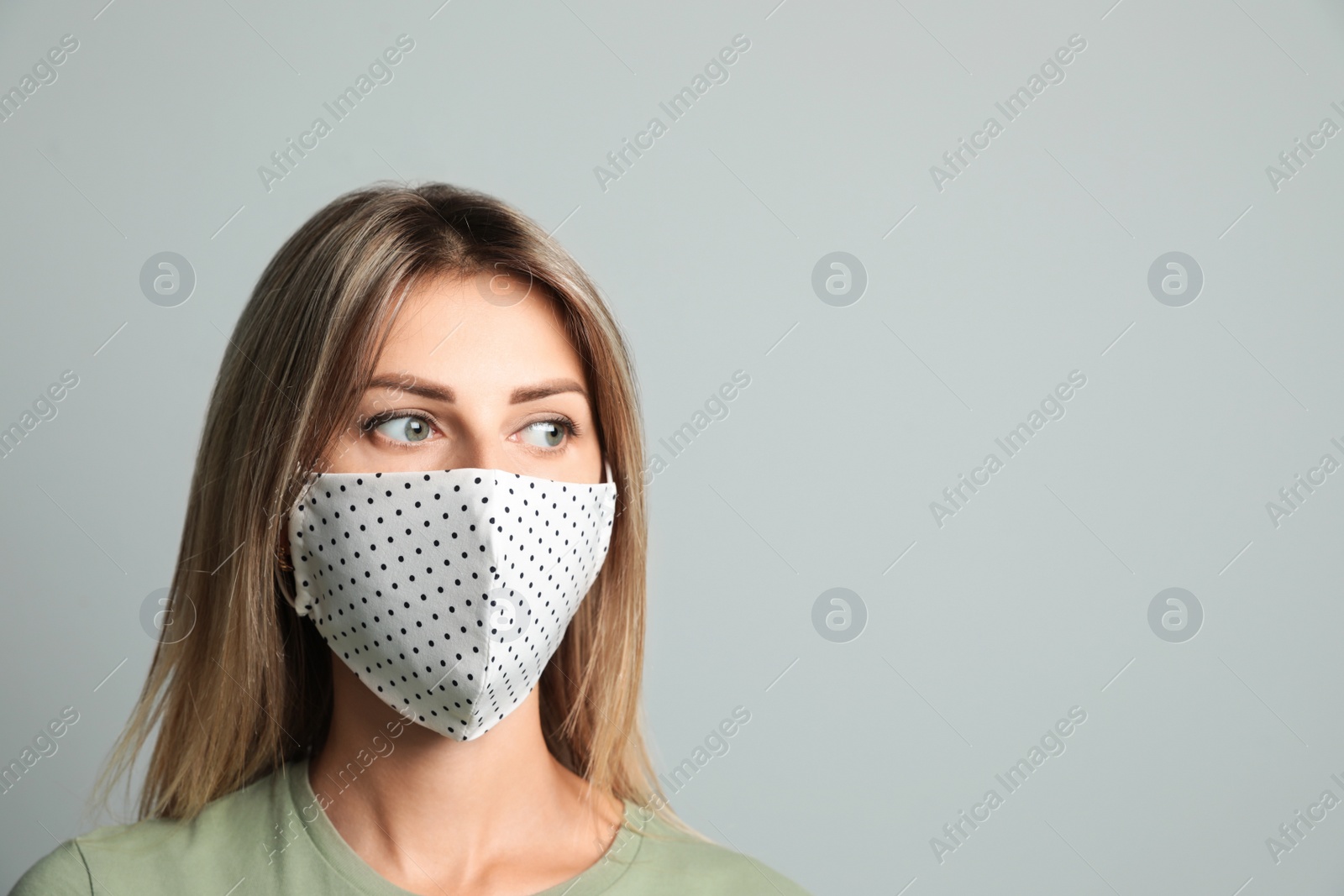 Photo of Young woman in protective face mask on light grey background. Space for text