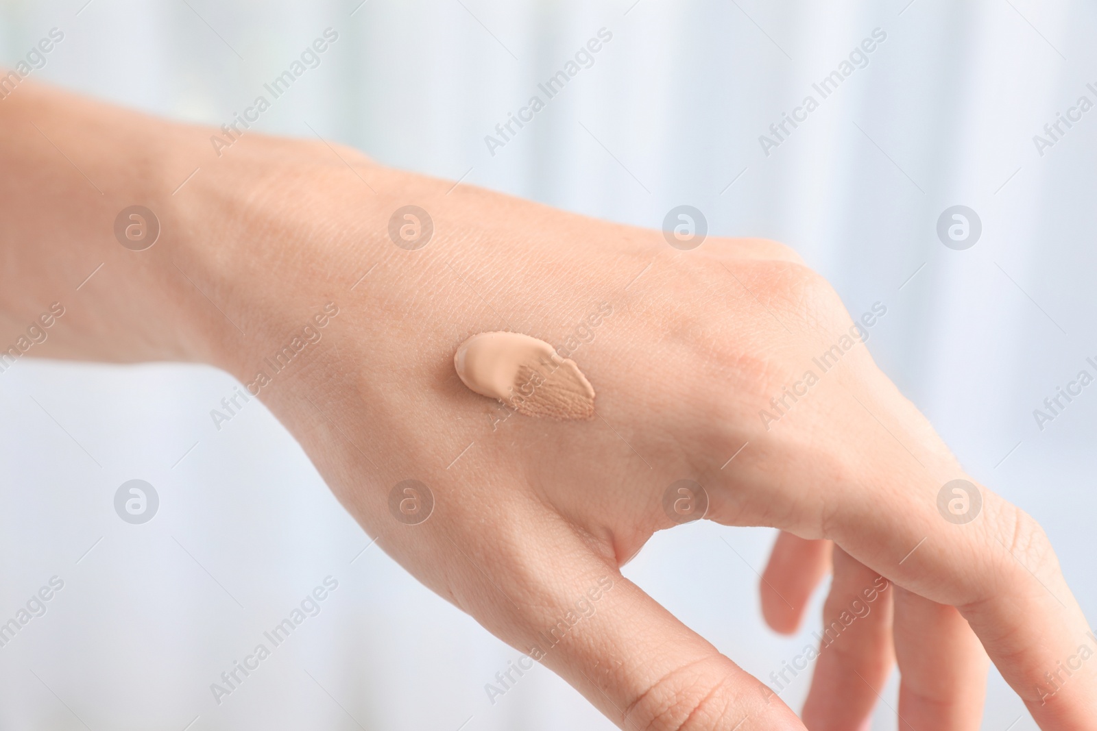 Photo of Woman testing foundation tone on hand, closeup