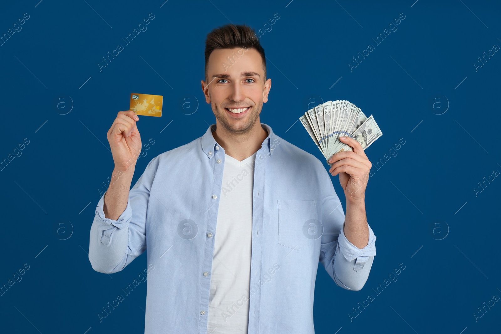 Photo of Happy man with cash money and credit card on blue background