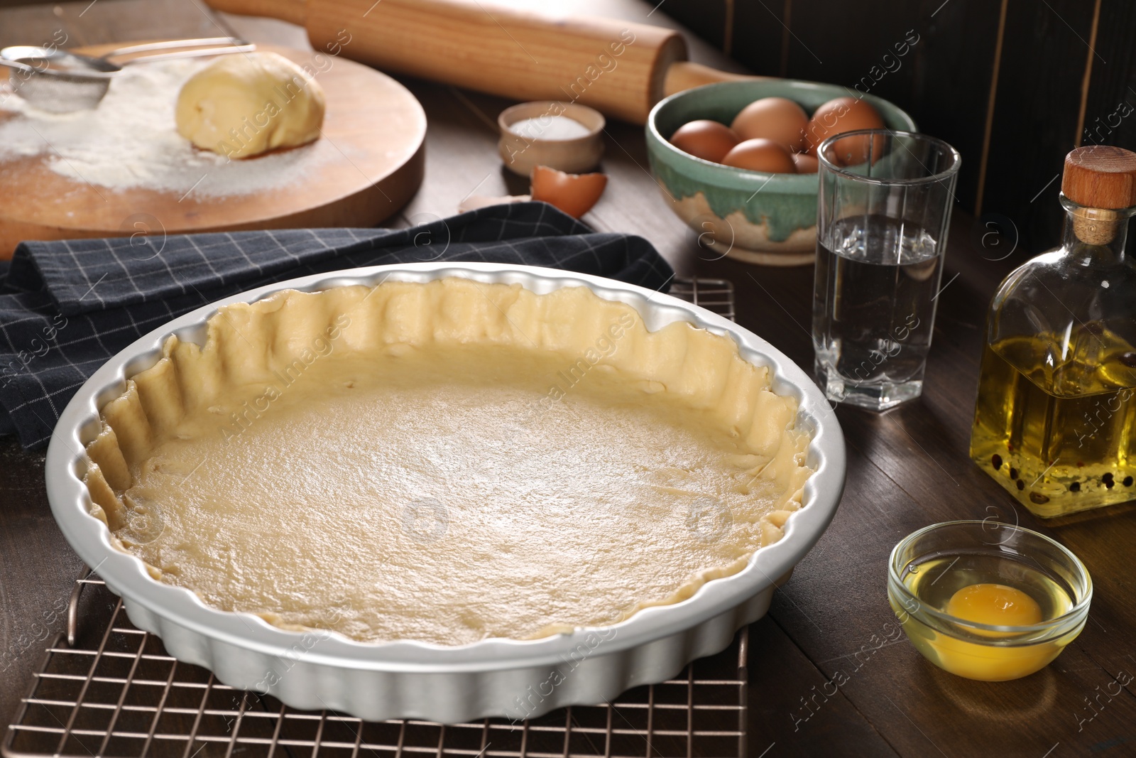 Photo of Pie tin with fresh dough and ingredients on wooden table. Making quiche