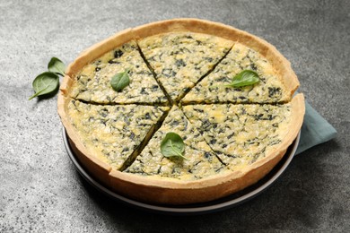 Plate of cut delicious spinach pie on grey table