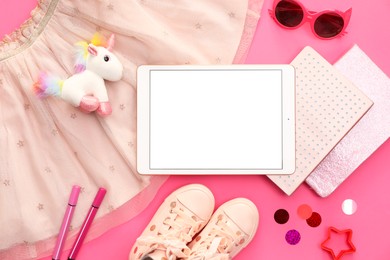 Modern tablet, skirt, toy unicorn and stationery on pink background, flat lay. Space for text