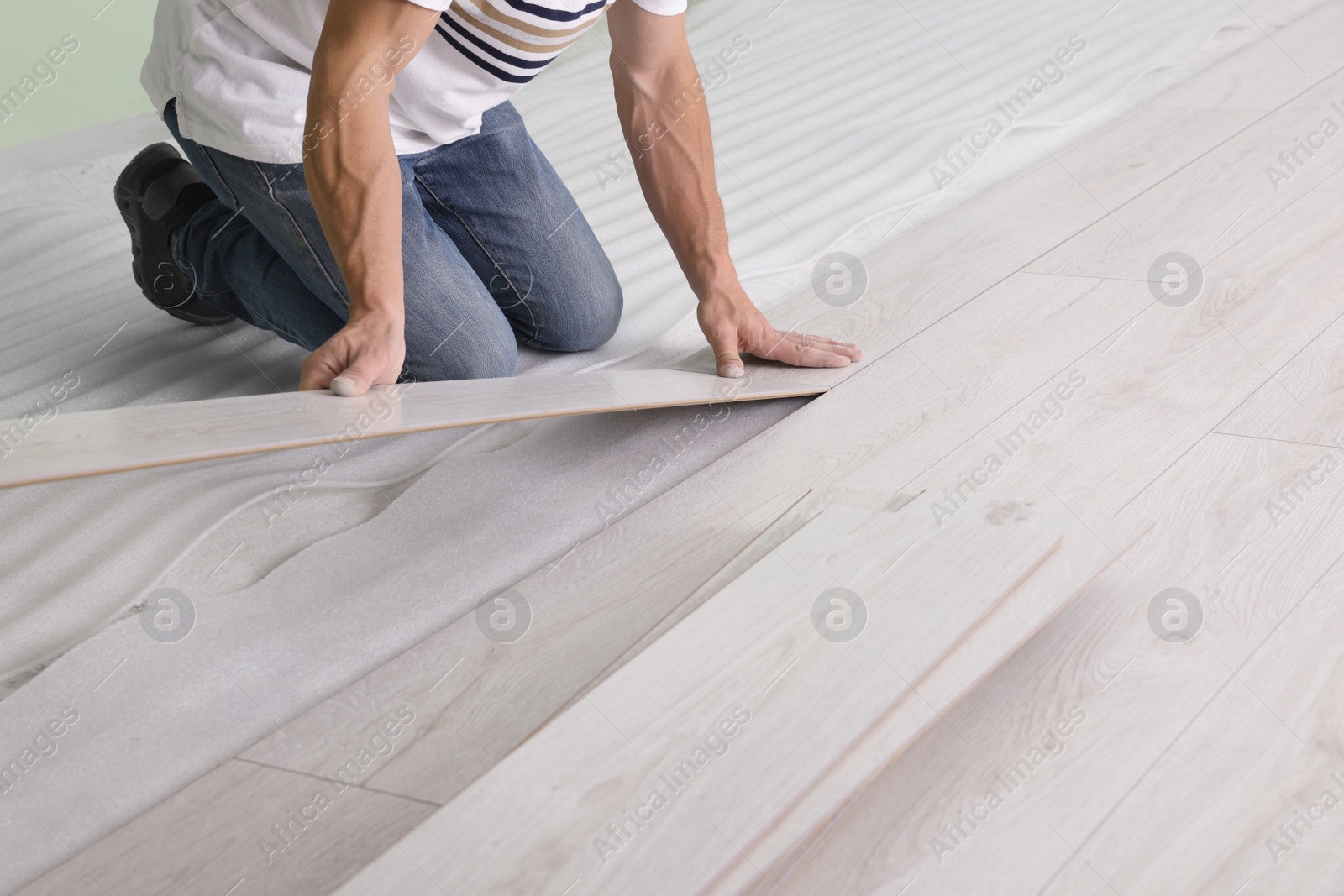 Photo of Man installing new laminate flooring indoors, closeup