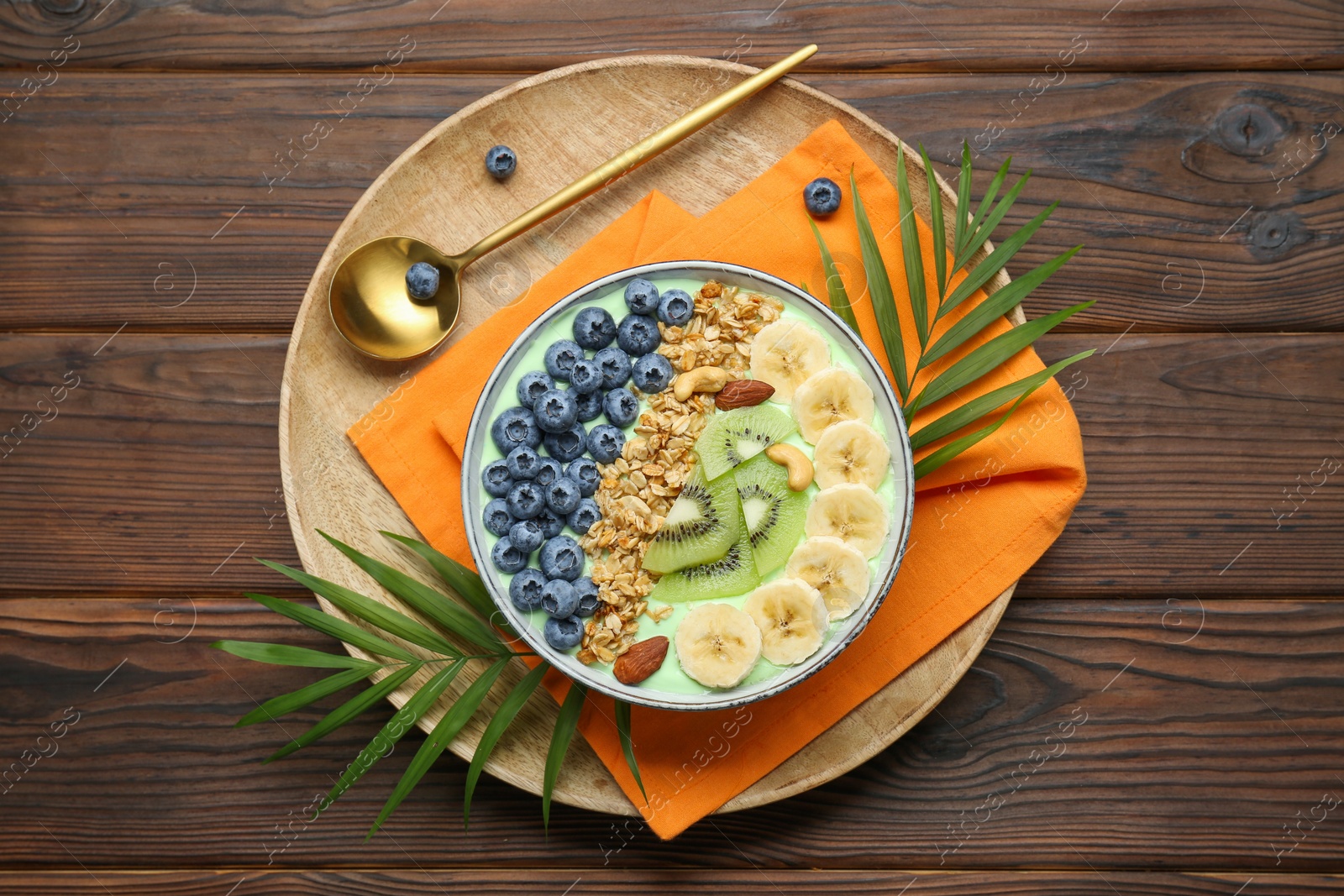 Photo of Tasty smoothie bowl with fresh fruits and oatmeal served on wooden table, top view