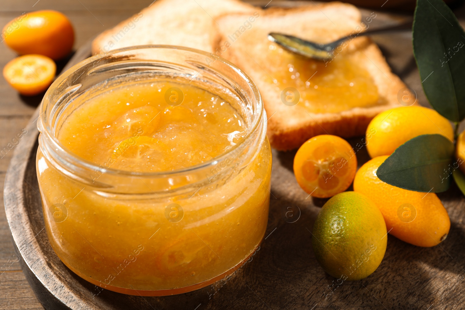 Photo of Delicious kumquat jam and fresh fruits on wooden tray