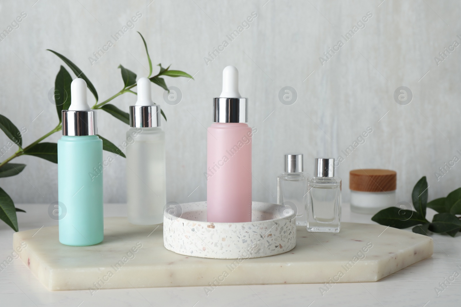 Photo of Bottles of serum and essential oil on white wooden table. Cosmetic products