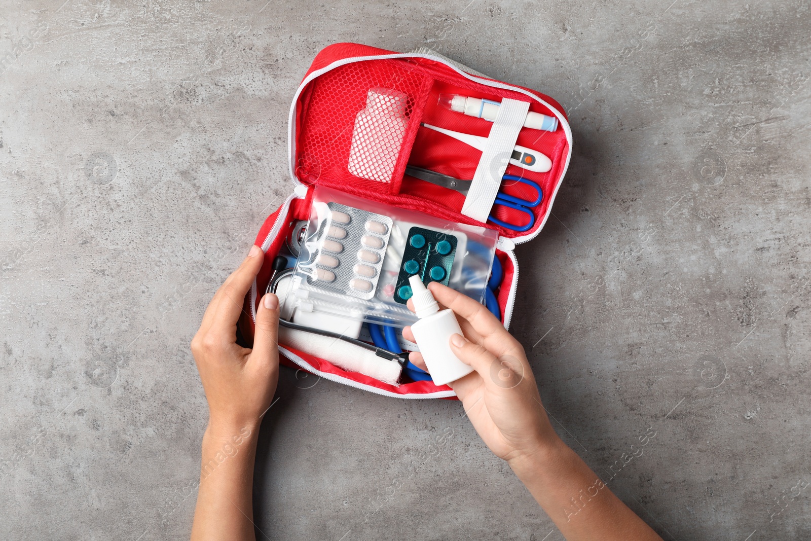 Photo of Woman with first aid kit on gray background, top view