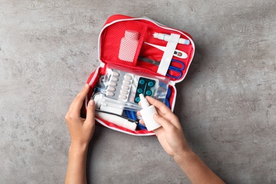 Photo of Woman with first aid kit on gray background, top view