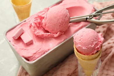 Photo of Delicious ice cream in container and wafer cones on table, closeup