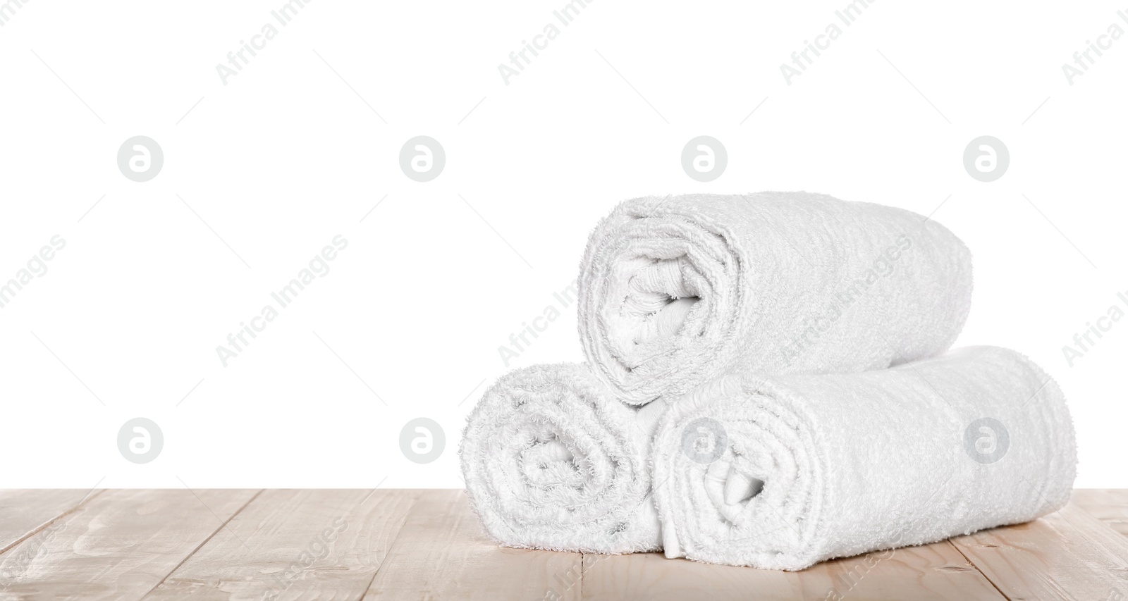 Photo of Soft terry towels on wooden table against white background, space for text