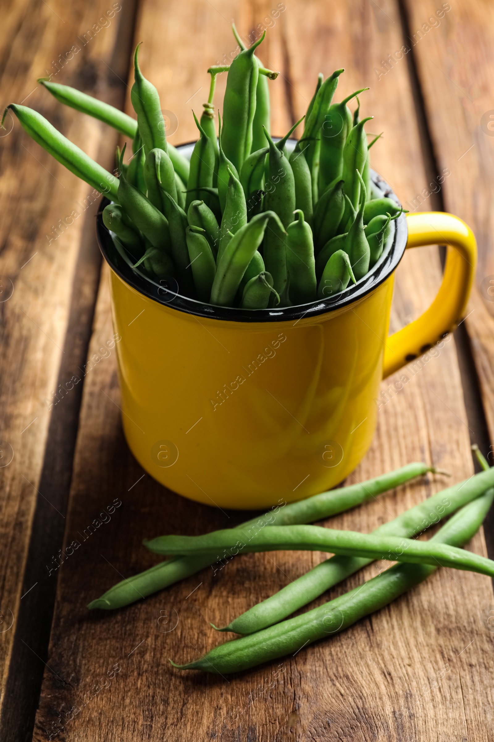 Photo of Fresh green beans in mug on wooden table