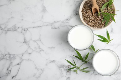 Photo of Hemp milk, seeds and fresh leaves on white marble table, flat lay. Space for text