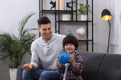 Photo of Little boy and his father with piggy bank at home