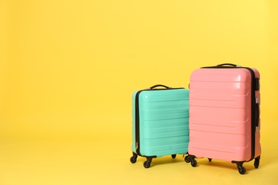 Photo of Stylish suitcases on color background. Space for text