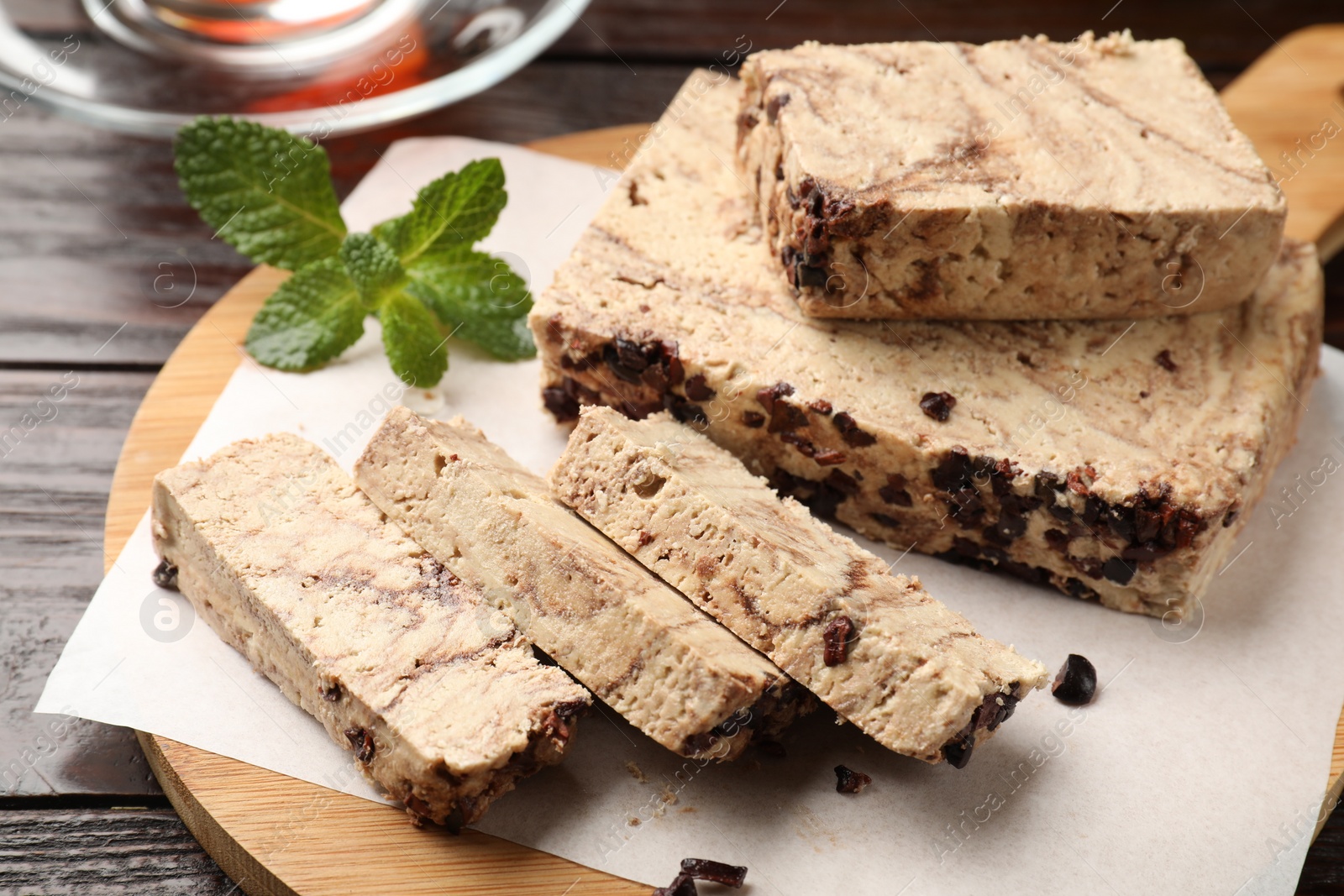 Photo of Pieces of tasty chocolate halva with mint on wooden table, closeup