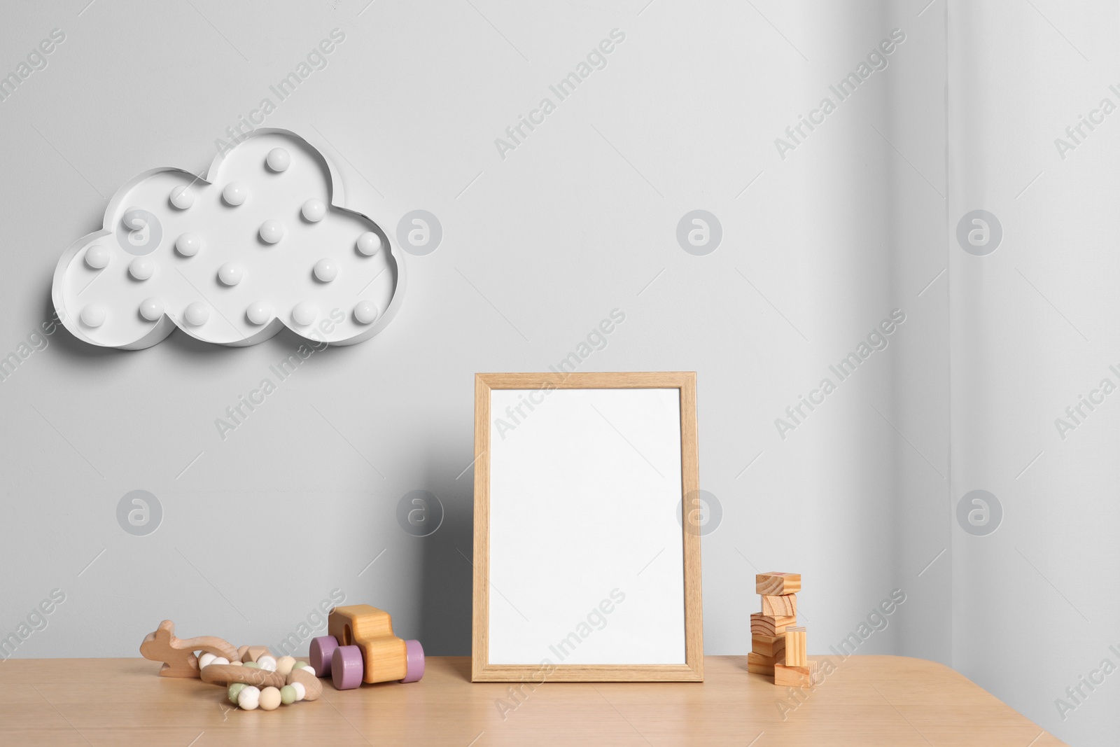 Photo of Empty square frame and different toys on wooden table indoors