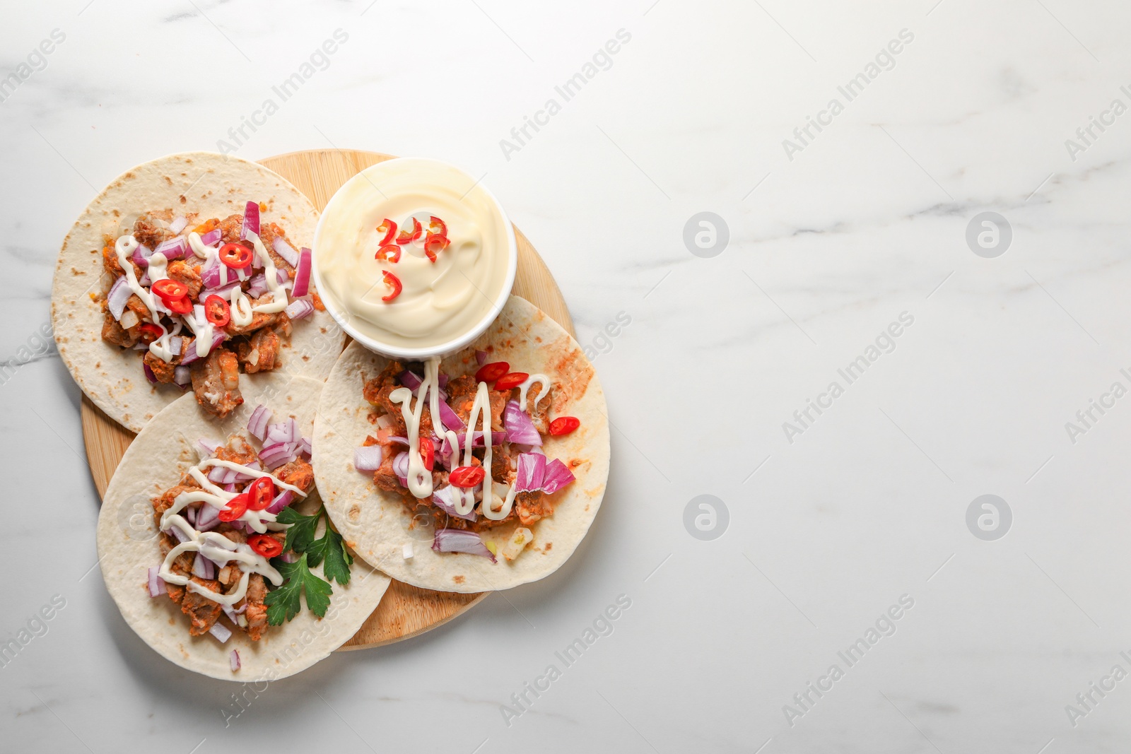 Photo of Delicious tacos with vegetables, meat and sauce on white marble table, top view. Space for text