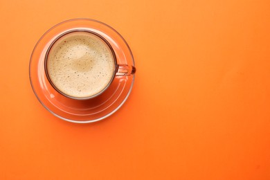 Fresh coffee in cup on orange background, top view. Space for text