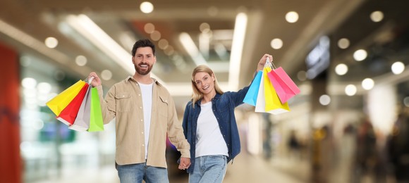 Image of Happy couple with shopping bags walking in mall, banner design