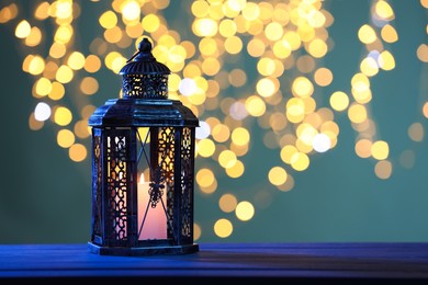 Photo of Traditional Arabic lantern on table against blurred lights at night. Space for text